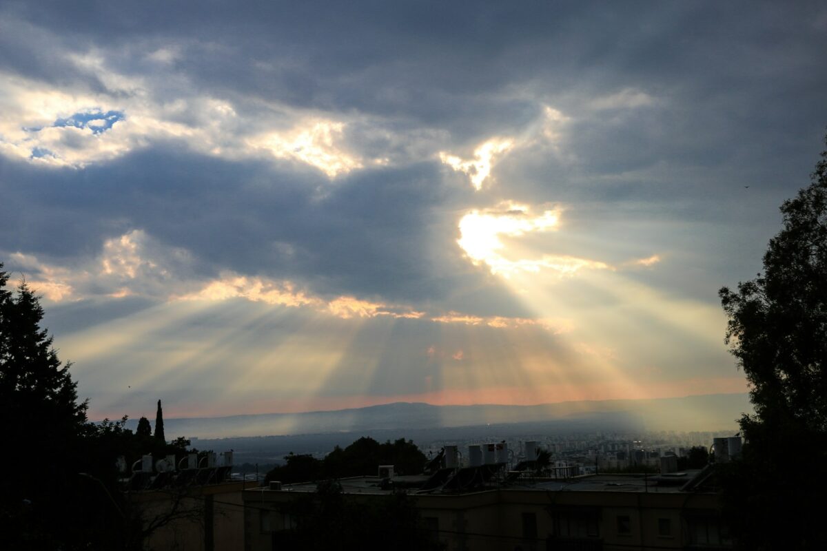 The sun is shining through the clouds over a city